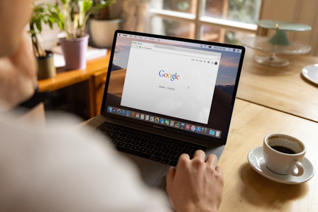 A person looks at a laptop screen that displays the Google search page.