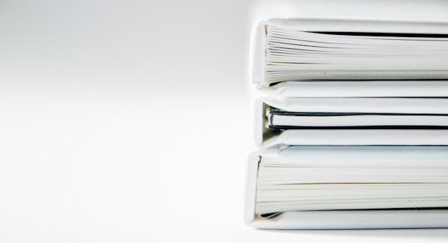 A close-up of a stack of three books with white covers.

