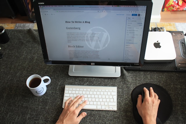 A person writes a blog on macOS using an HP monitor and Apple keyboard.