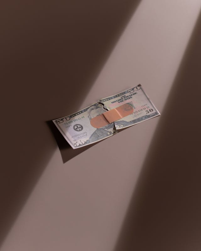 A 50 US dollar bill in two pieces with a brown adhesive bandage over it