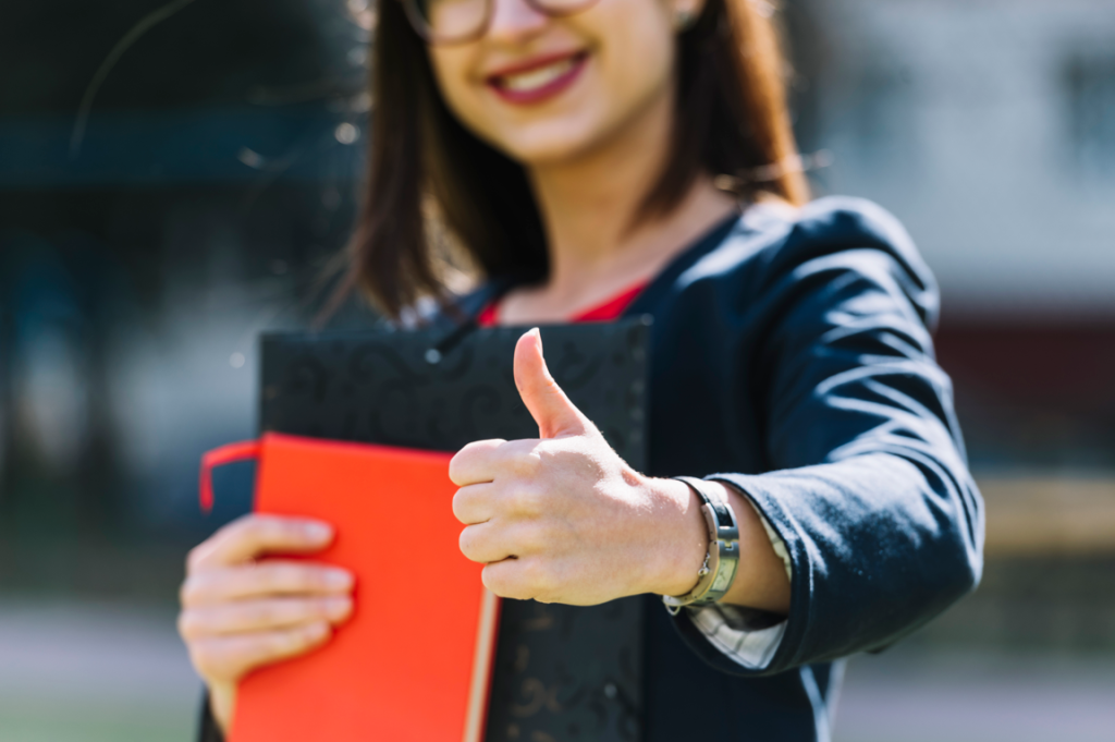 A happy woman with documents giving a thumbs-up.