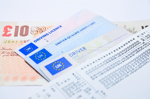 UK driving licence cards, driver qualification card, and paperwork placed on top of a £10 banknote.